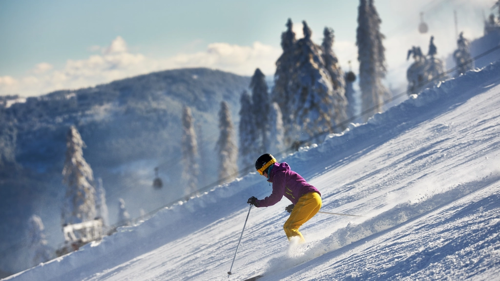 Skifahrer in bunter Kleidung fährt einen schneebedeckten Hang hinunter