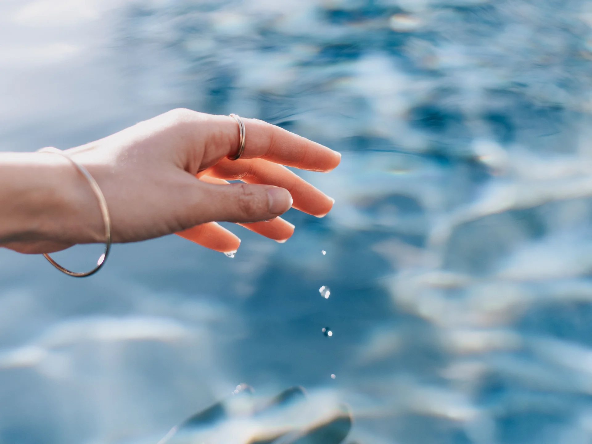 Cubea | Anreise und häufig gestellte Fragen Hand berührt Wasseroberfläche mit fallenden Wassertropfen