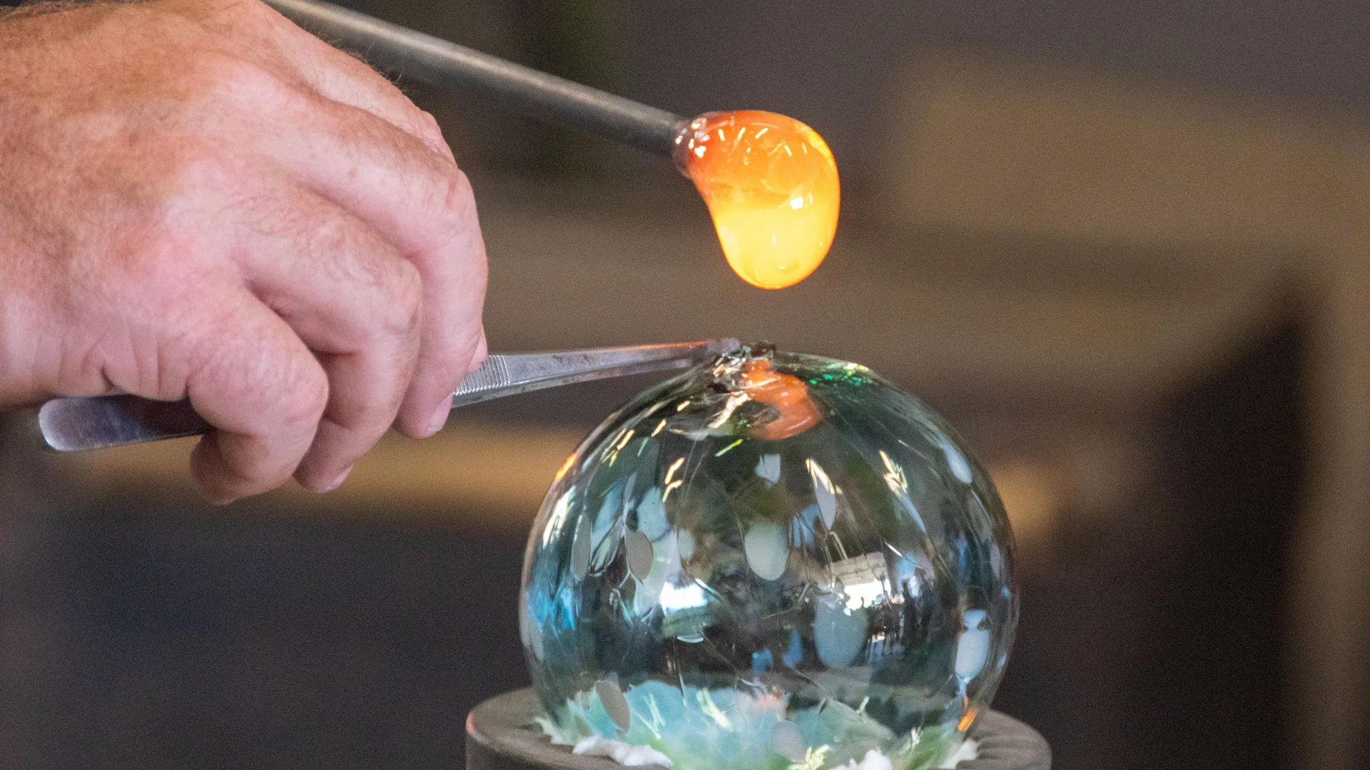 Cubea | Urlaub³ im Bayerischen Wald Hand formt glühendes Glas auf einer Glasbläserwerkbank