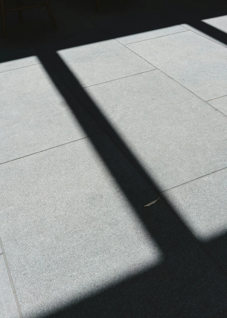 Schatten eines Fensters auf grauen Bodenfliesen