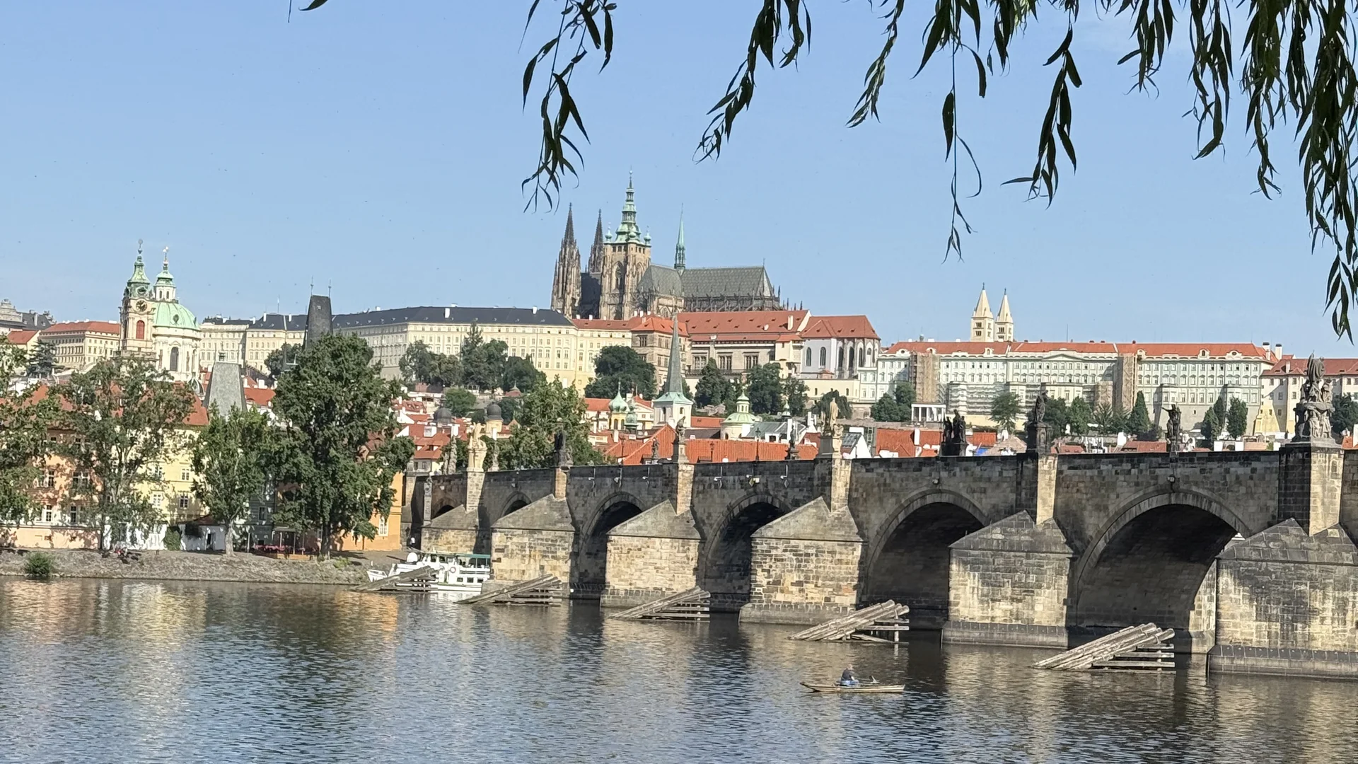 Cubea | Urlaub³ im Bayerischen Wald Blick auf die Karlsbrücke und Prager Burg mit Fluss und Baumzweigen im Vordergrund