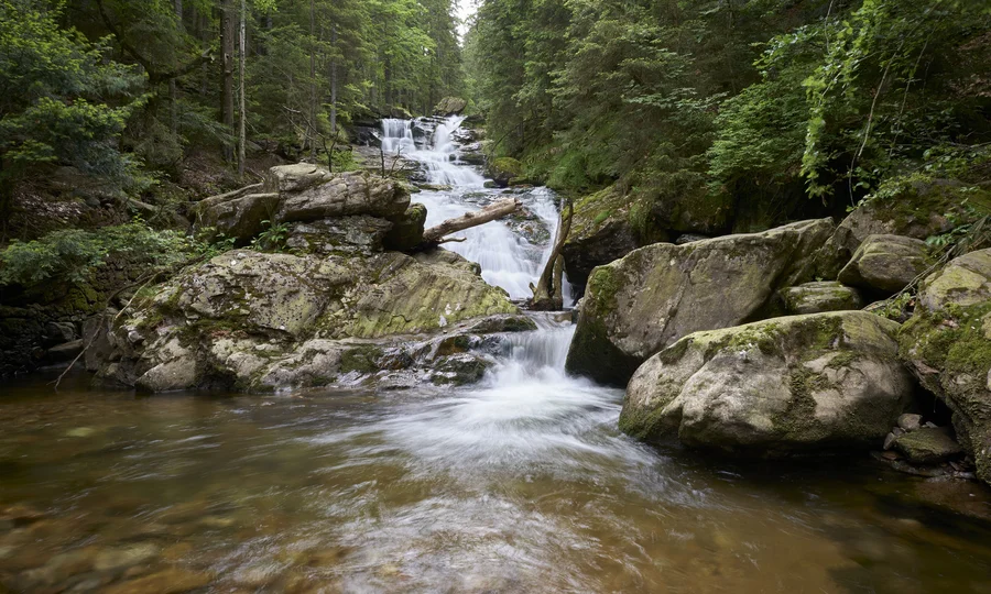 Wasserfall im Wald mit großen Felsen und fließendem Wasser