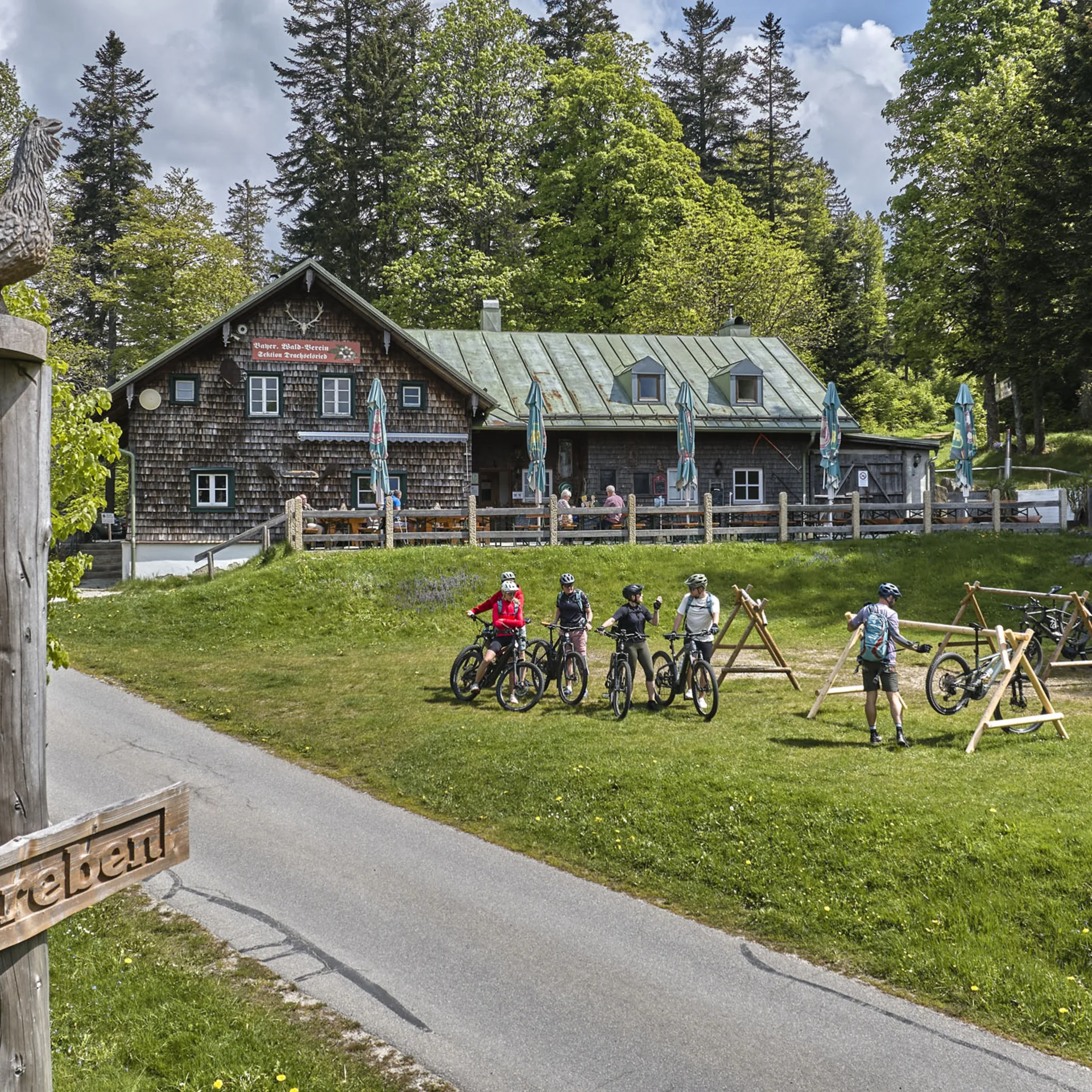 Holzhaus mit Terrasse und Radfahrern auf einer Wiese im Wald bei Schareben