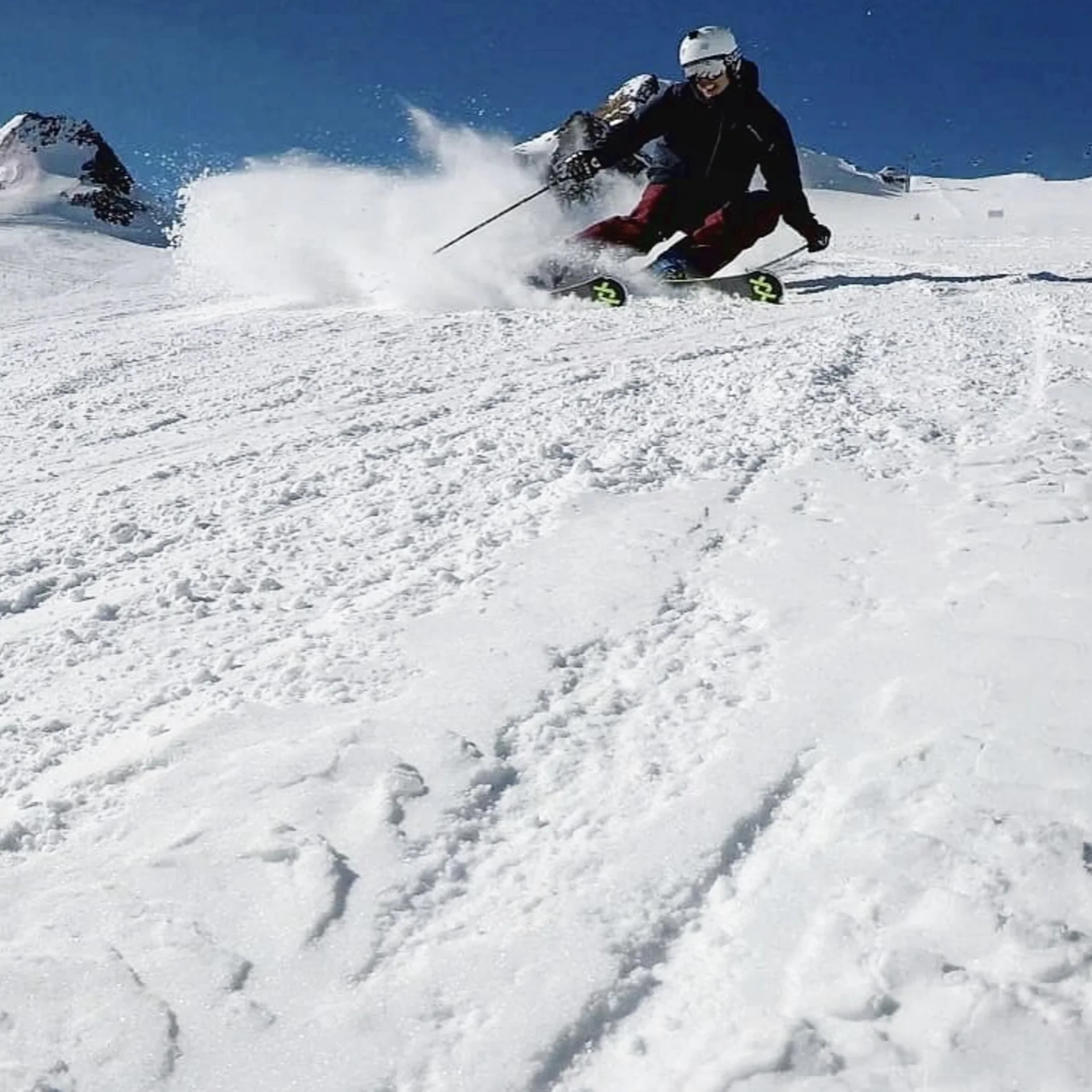 Skifahrer fährt schnell den schneebedeckten Hang bei klarem Himmel hinunter