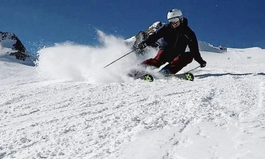 Skifahrer fährt schnell den schneebedeckten Hang bei klarem Himmel hinunter