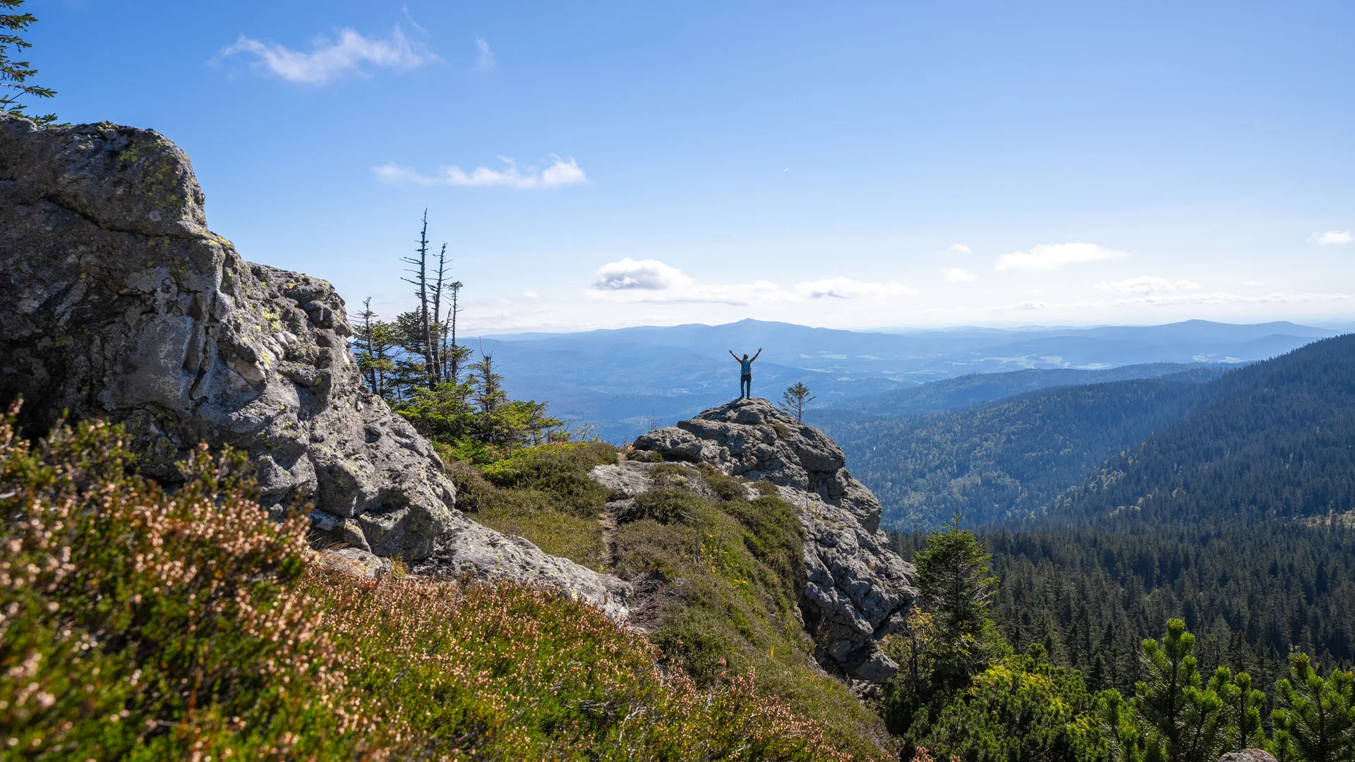 Cubea | Urlaub³ im Bayerischen Wald Person steht auf Felsen mit ausgestreckten Armen in Berglandschaft