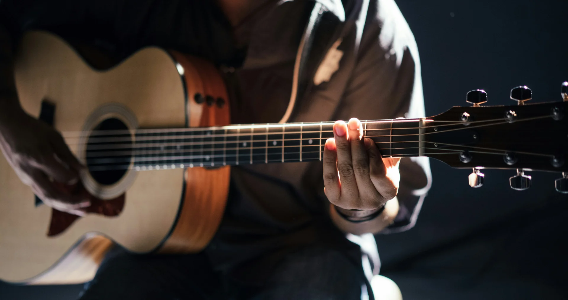 Cubea | Urlaub³ im Bayerischen Wald Person spielt akustische Gitarre in dunkler Umgebung