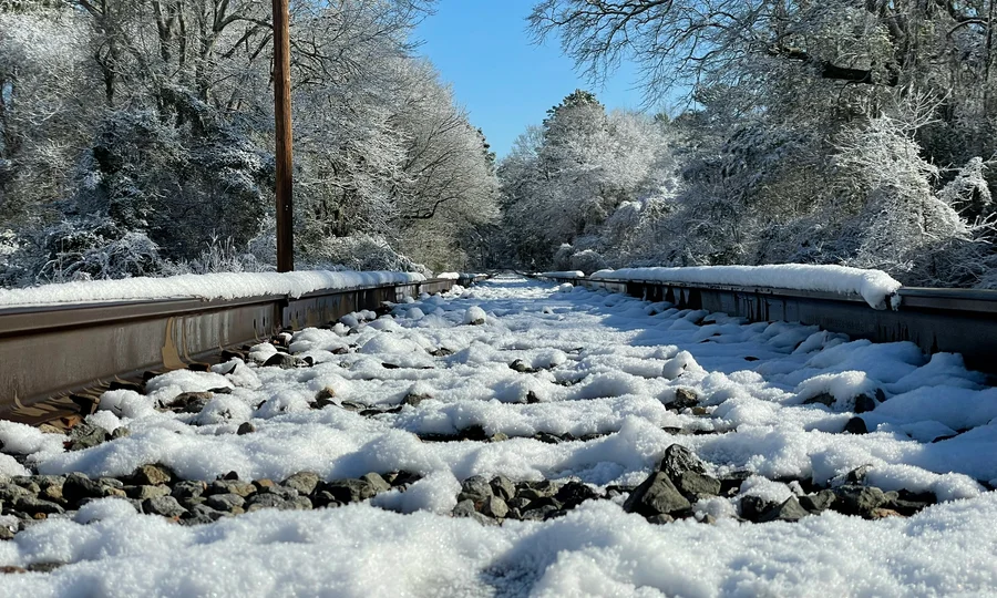 Cubea | Anreise und häufig gestellte Fragen Schneebedeckte Eisenbahnschienen mit Bäumen im Winter bei klarem Himmel